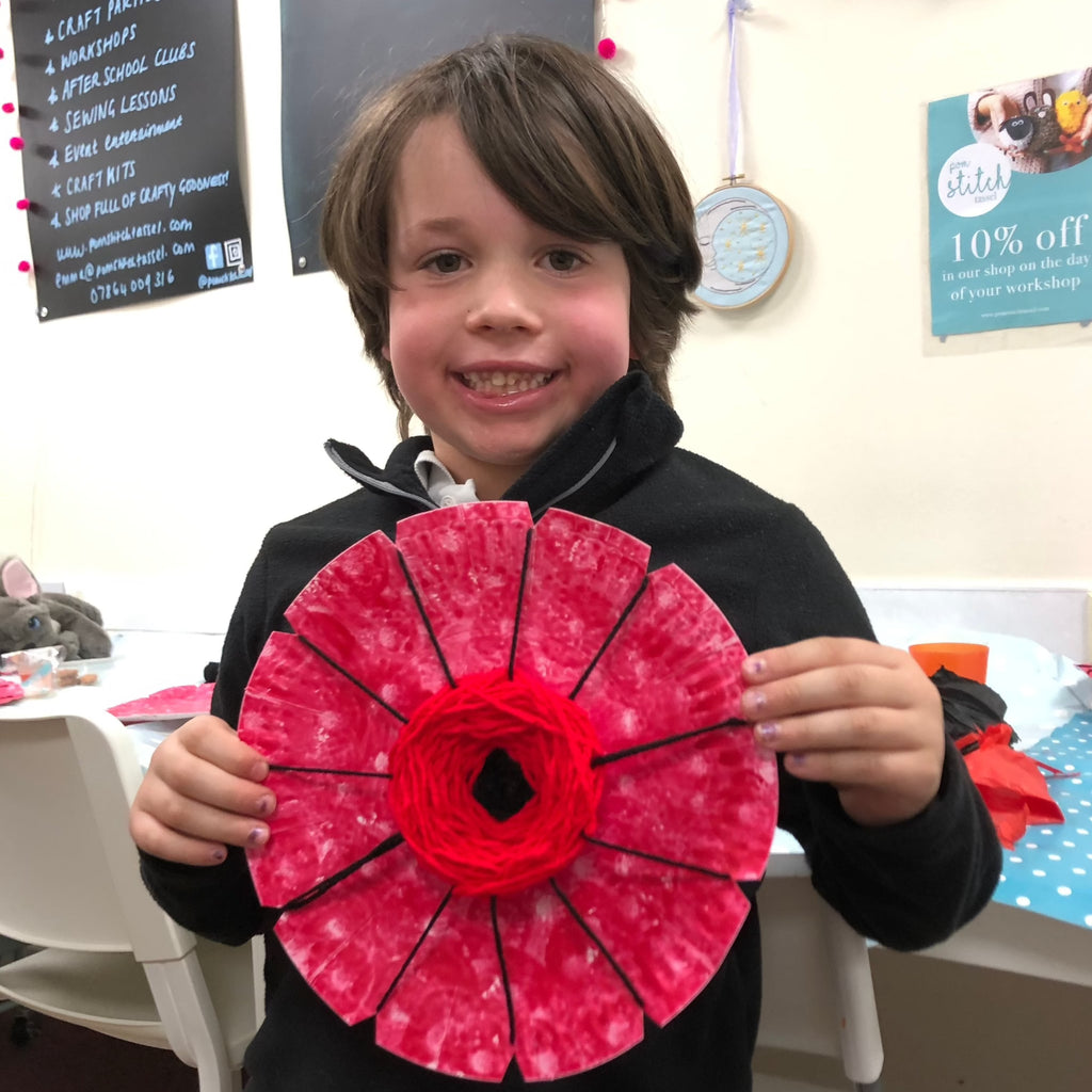 little boy showing his paper plate poppy with craft mess in background!