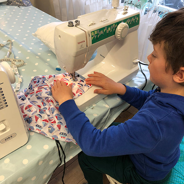 little boy sewing on sewing machine using nautical fabric.