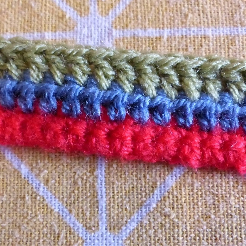 crochet yarn on patterned background - green, blue and red yarn crocheted.