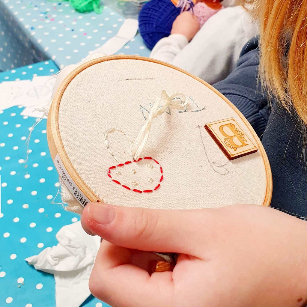 Embroidery hoop in girls hands with needle and thread sewing.