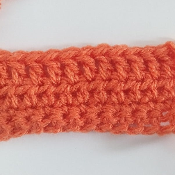 orange yarn crocheted on a white background - crochet workshop at pom stitch tassel.