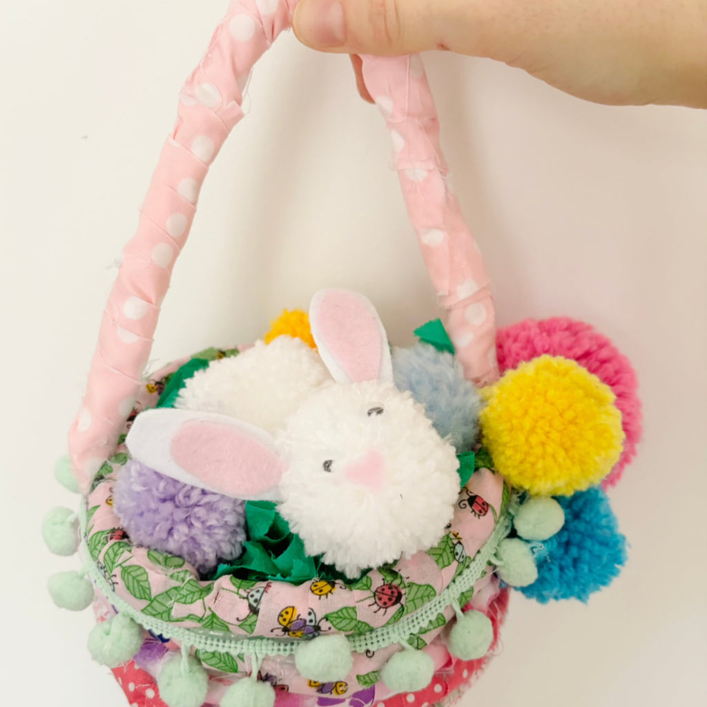 Hand holding pomPom spring basket with Pom Pom bunny.