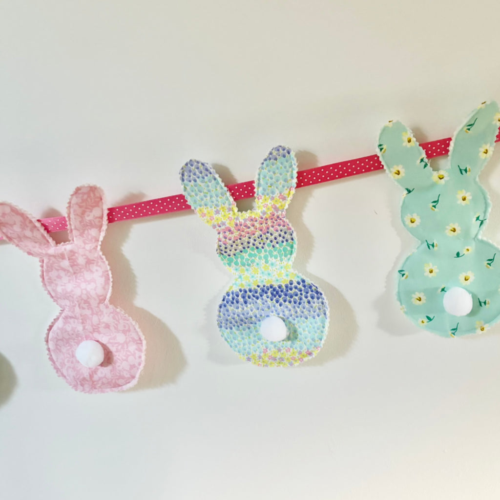 Patterned fabric cut into bunny shapes and sewn into bunny bunting with Pom Pom tails. Easter holiday workshop at Pom stitch tassel.