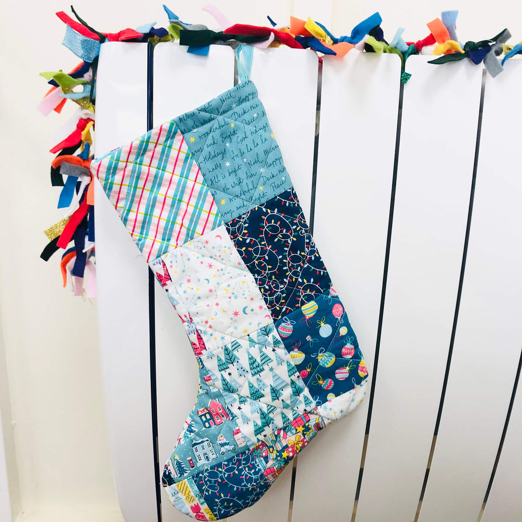 Patchwork stocking in blue hanging on radiator with felt garland.