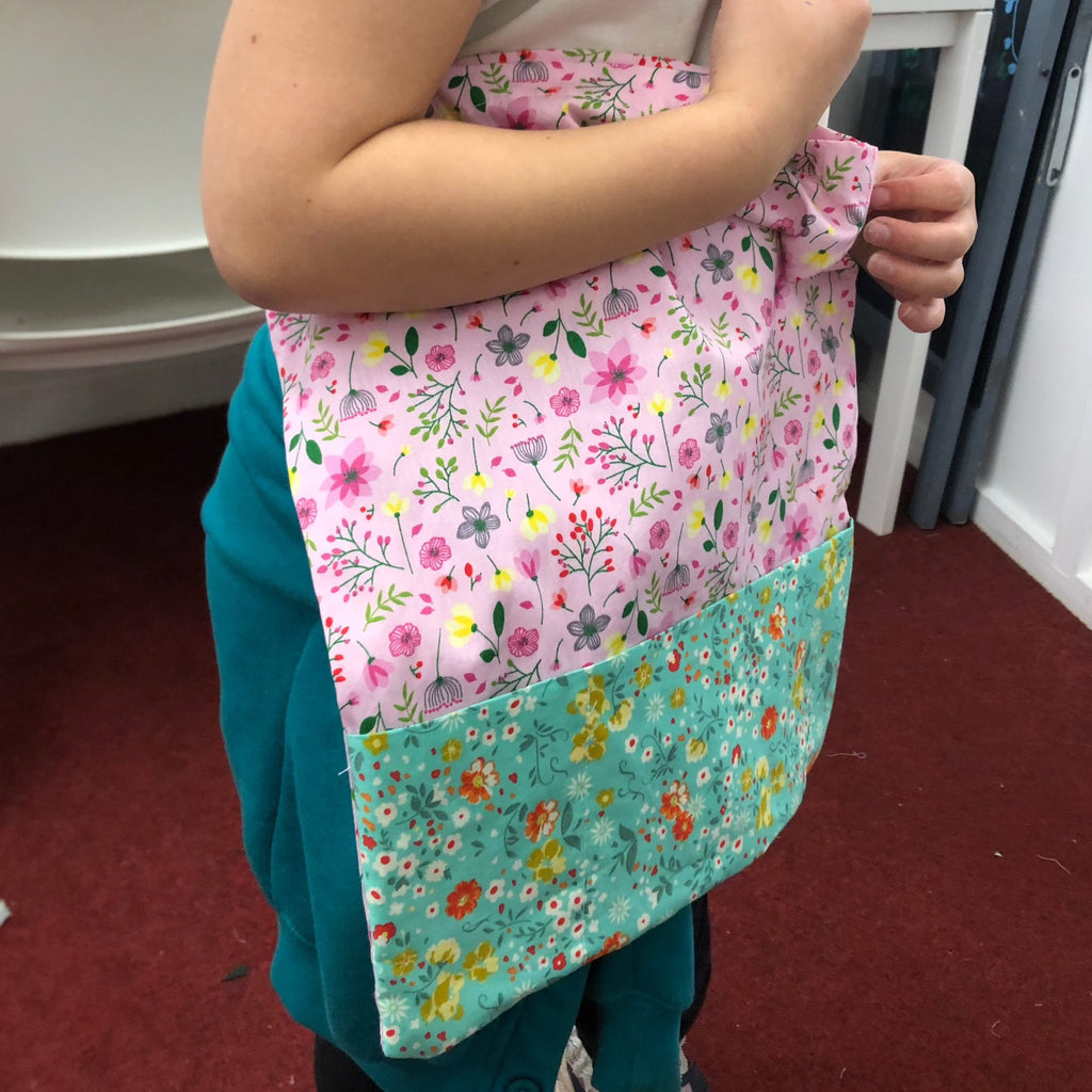 little girl showing off her tote bag she made at stitch club with pom stitch tassel.