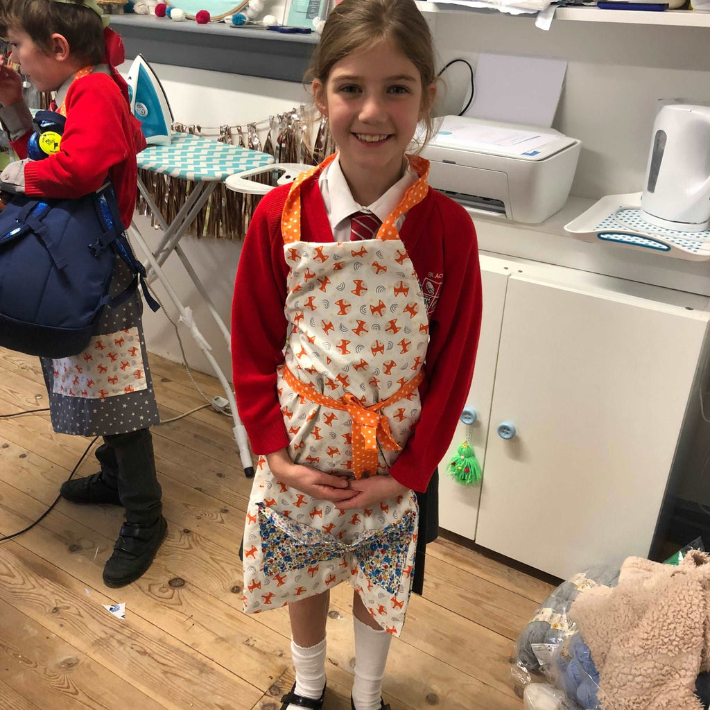 Home Education Stitch Club - young girl with handmade apron at stitch club. Printer, kettle and ironing board in background.