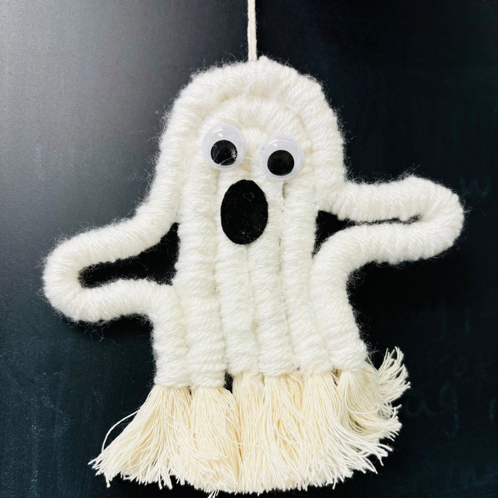 macrame ghost hanging on black background