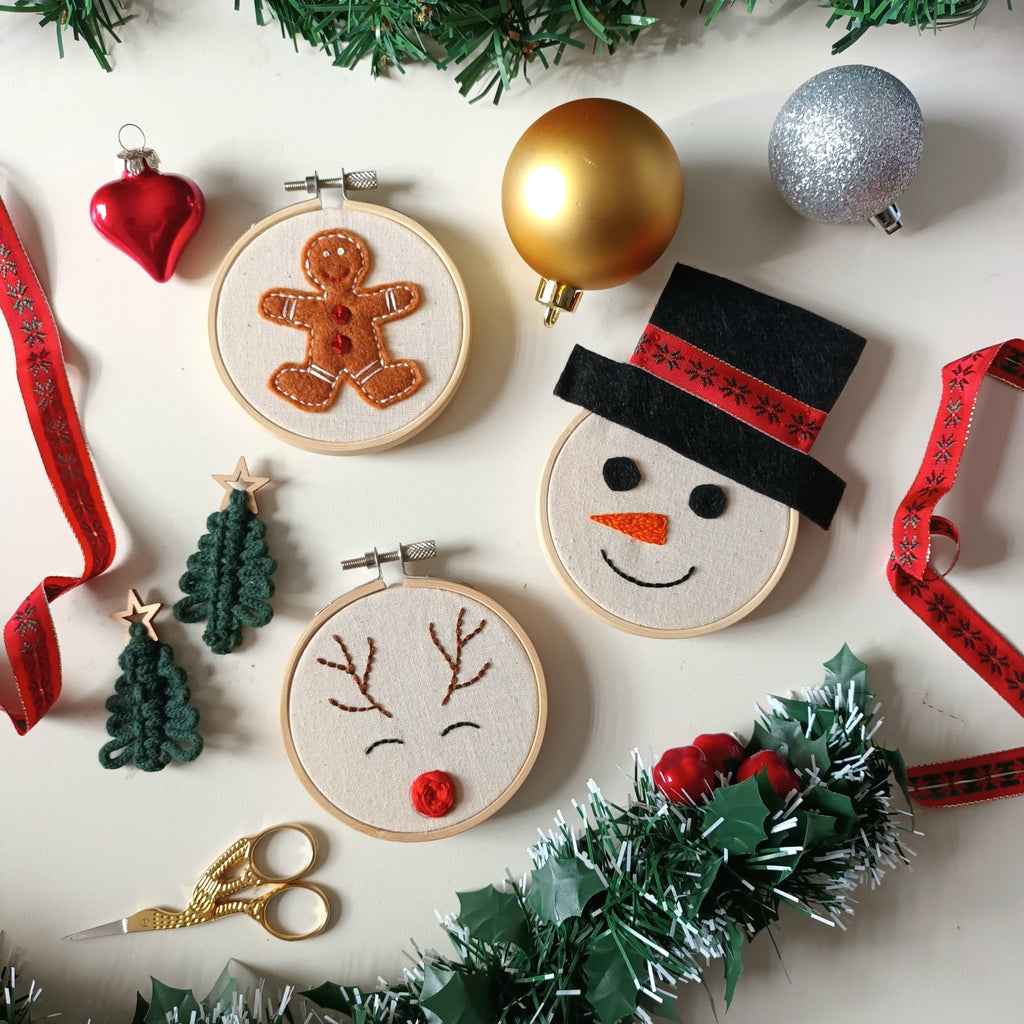 flatlay of emroidery hoops with stitching - gingerbread, snowman and reindeer.