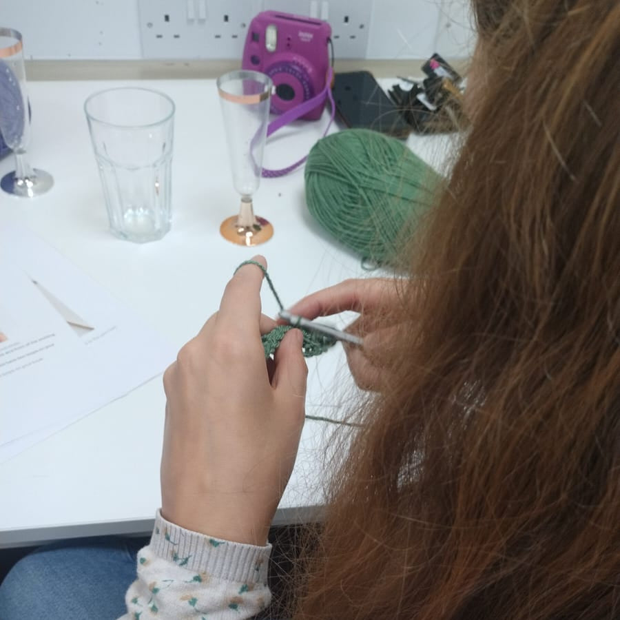lady crochetting with green wool
