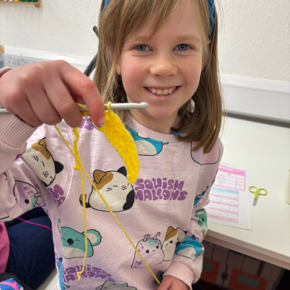child crocheting with yellow wool