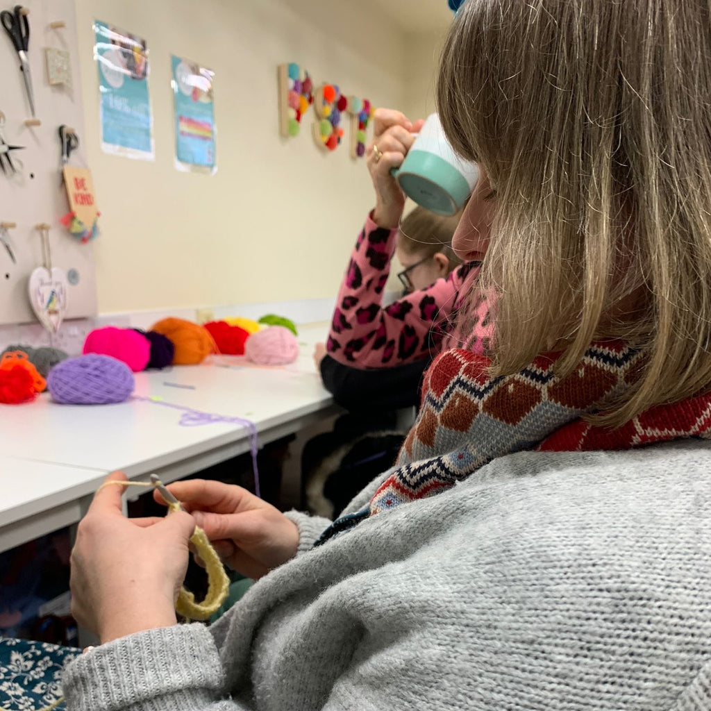 Lady learning to crochet with yellow yarn and crochet hook.