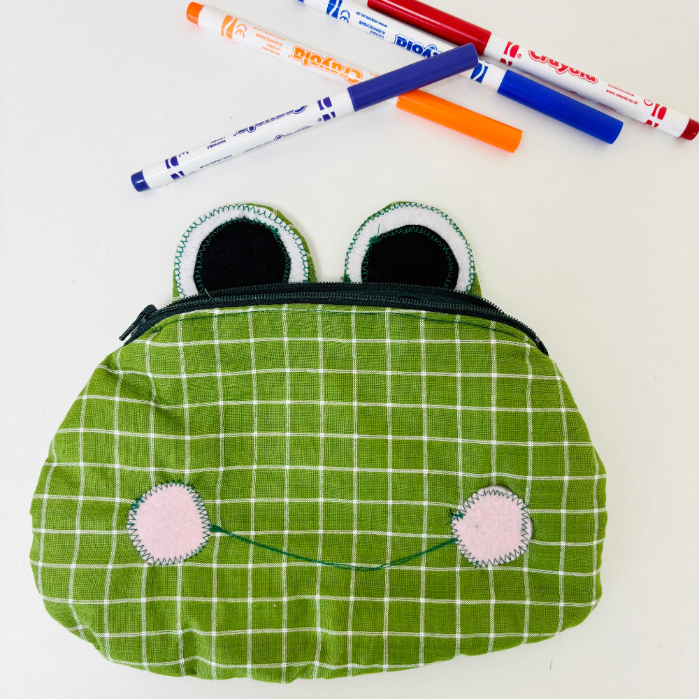 frog pencil case and crayola pens on white background