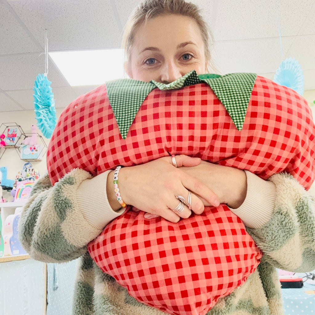 emma the founder of pom stitch tassel hugging a strawberry cushion. february half term workshop - learn to sew.