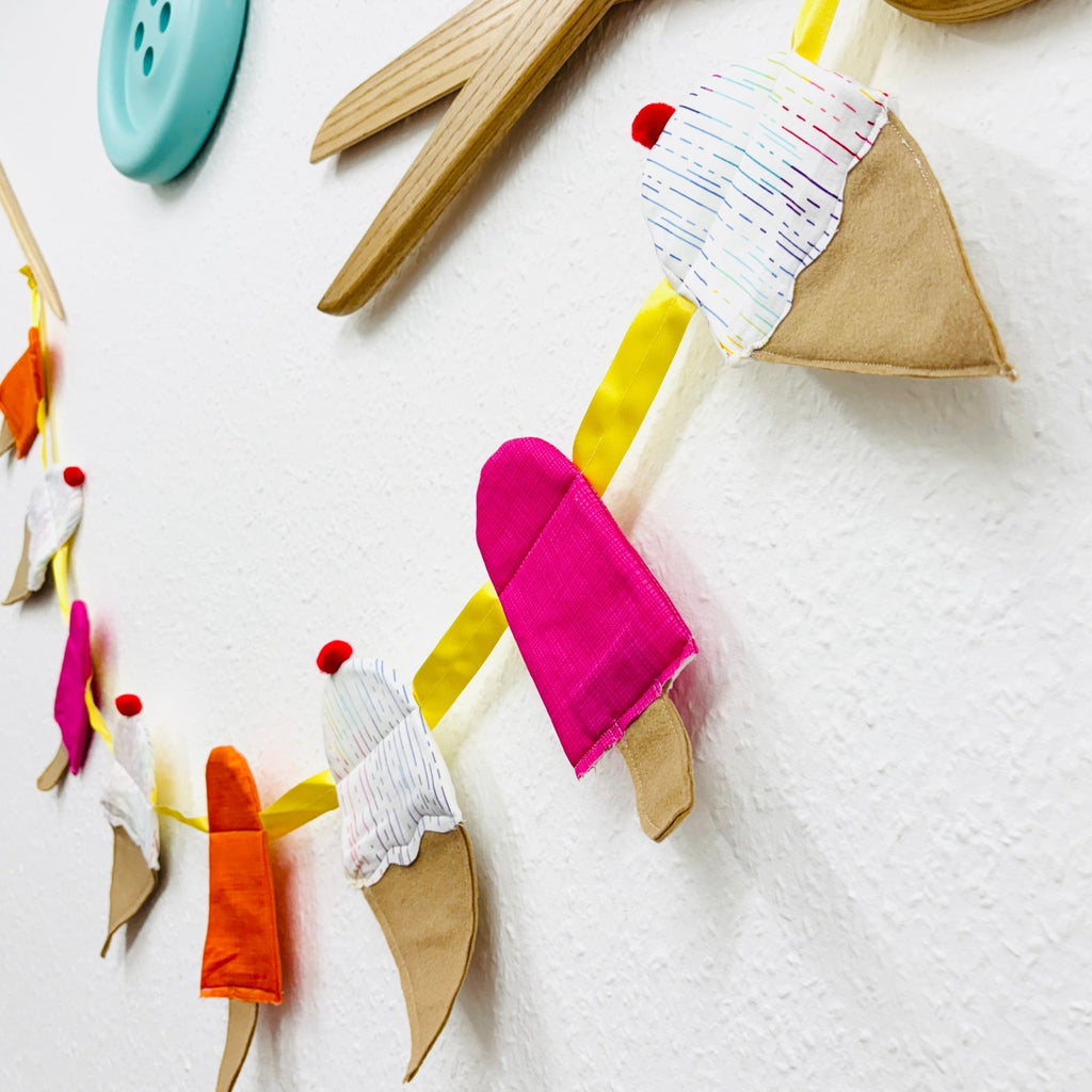 ice cream garland and giant wooden button and scissors on white wall