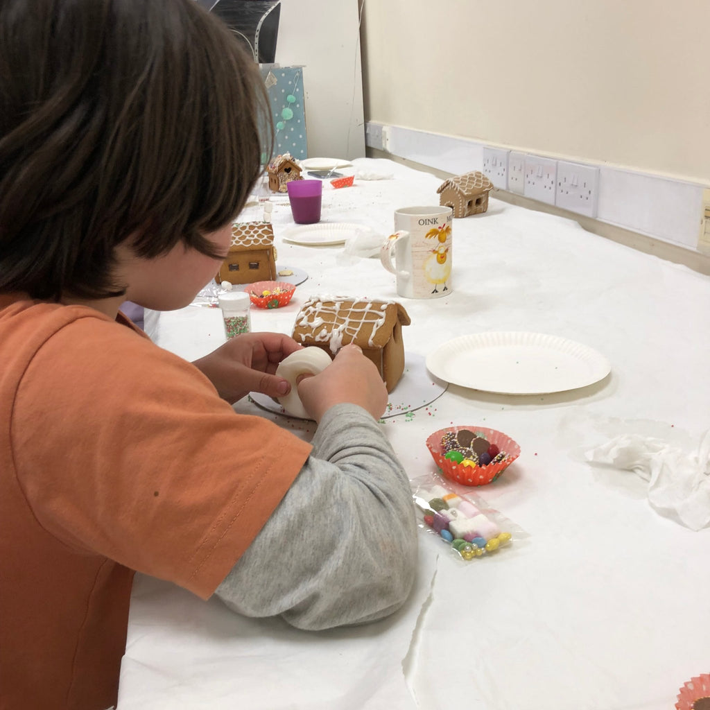 little boy decorating a gingerbread house