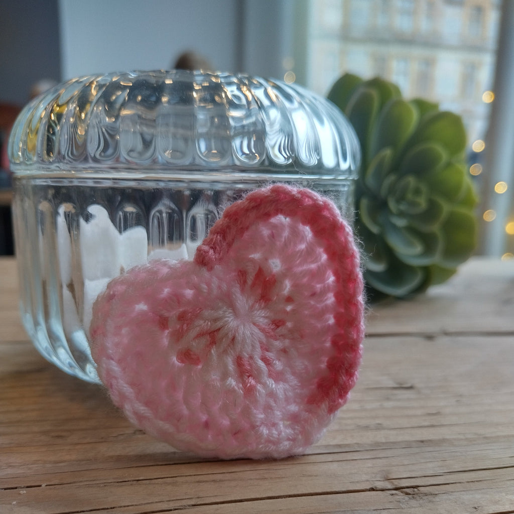 pale pink crochet heart on wooden table.