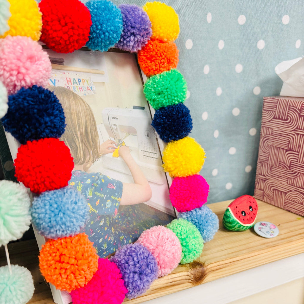 a photo of a little girl sewing in a pom pom photo frame