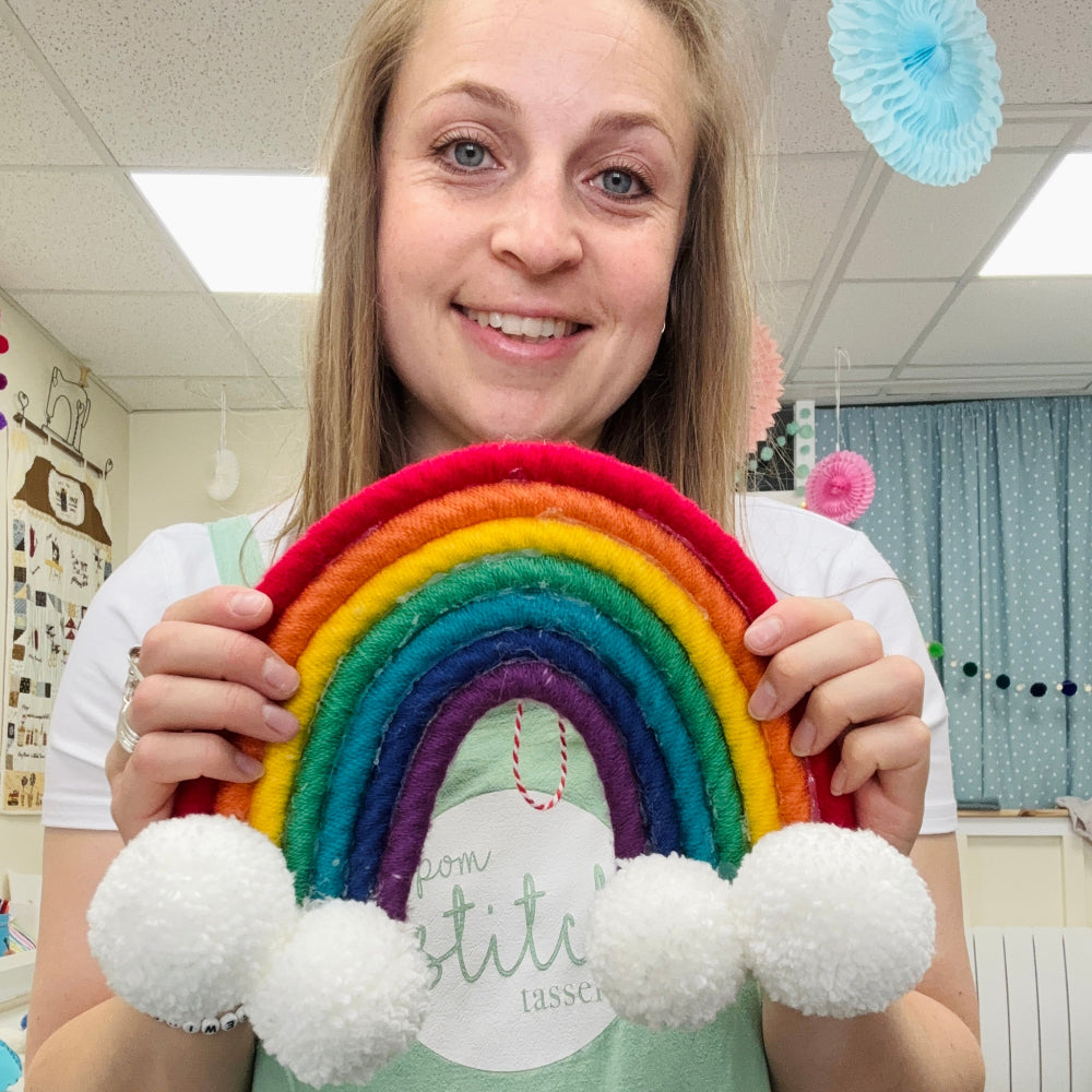 rainbow with pom pom clouds held in emmas hands