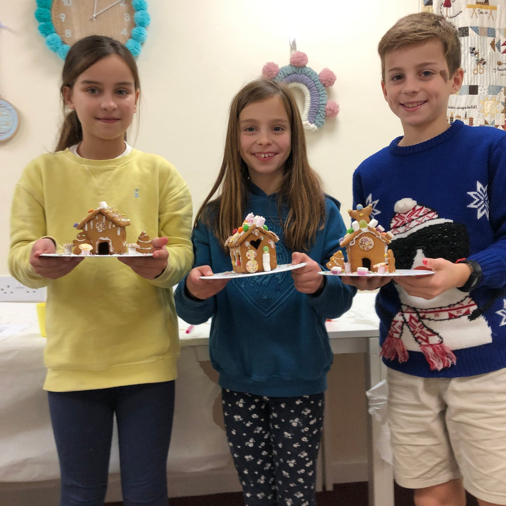 three siblings making and decorating their own gingerbread houses