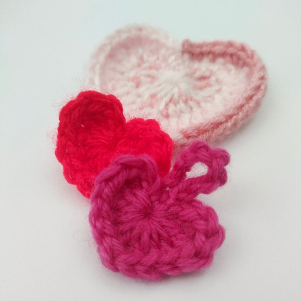 valentines day workshop - create your own crochet hearts - three crochet hearts in pink and red yarn.